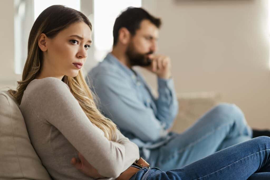 Picture of a couple looking unhappy while sitting on a couch for the blog 7 signs your marriage is not working