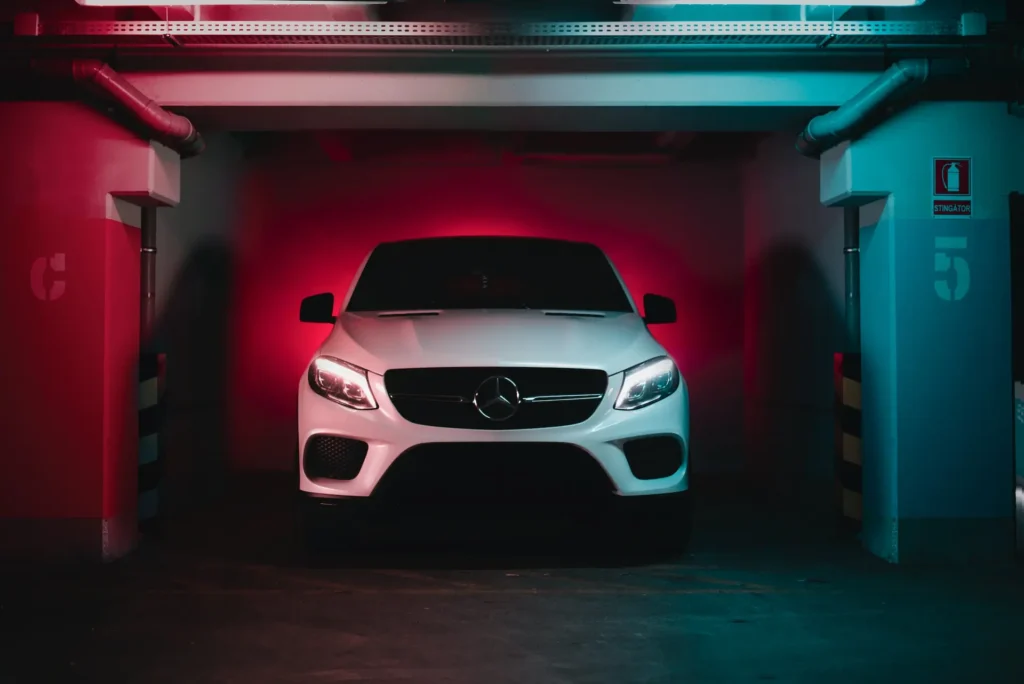Picture of a car in a garage with red and blue lights in the background for the article about the consequences of a hit and run car accident.